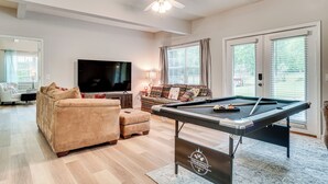 A living room with a pool table, a sofa, a television, and a ceiling fan. - Pet-friendly Georgia Home w/ Pool Access! (Cleveland)