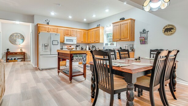 A modern kitchen with wooden cabinets, a central island, and a dining area with a wooden table and chairs. - Pet-friendly Georgia Home w/ Pool Access! (Cleveland)