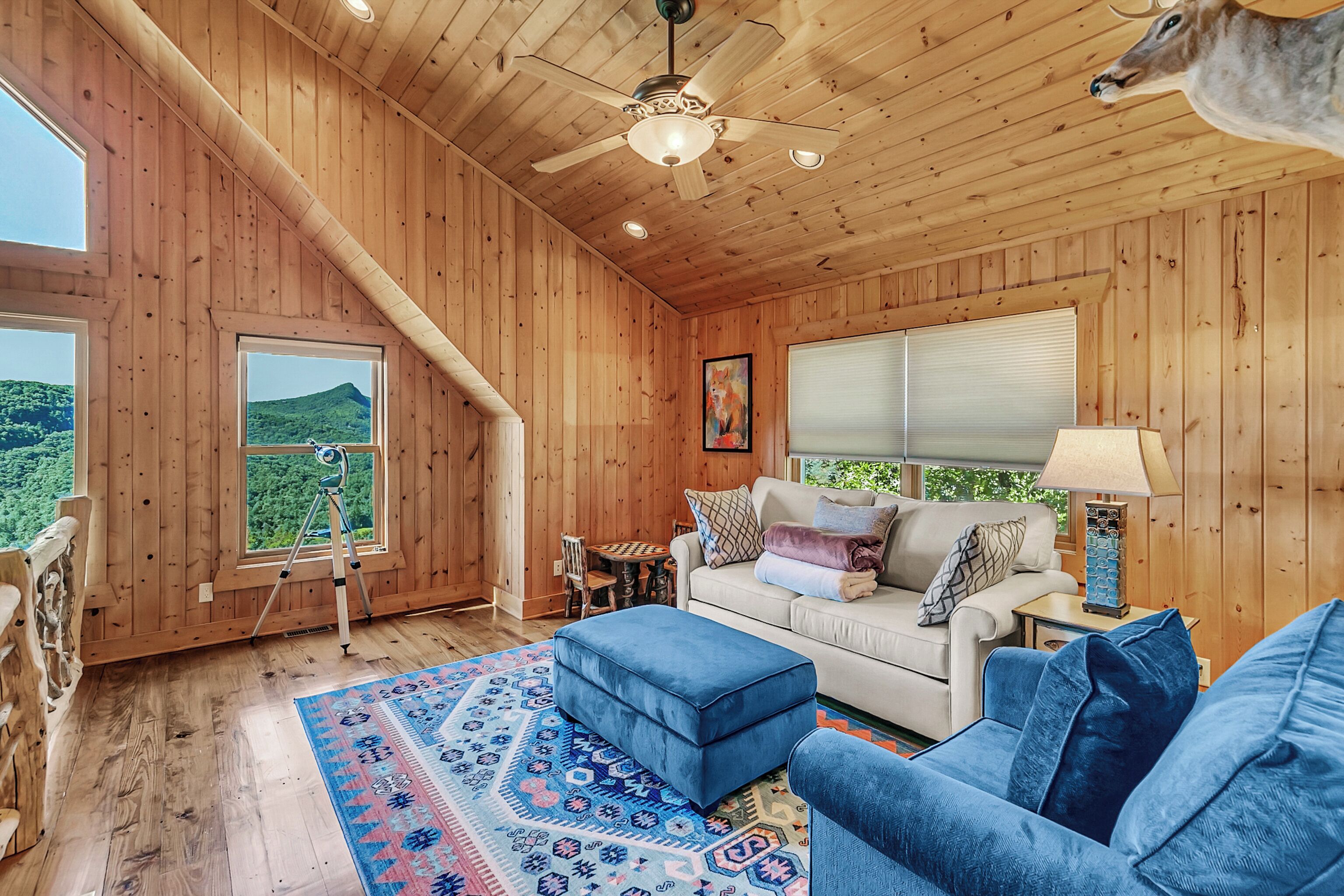 A wooden interior with a sofa, ottoman, and a ceiling fan.