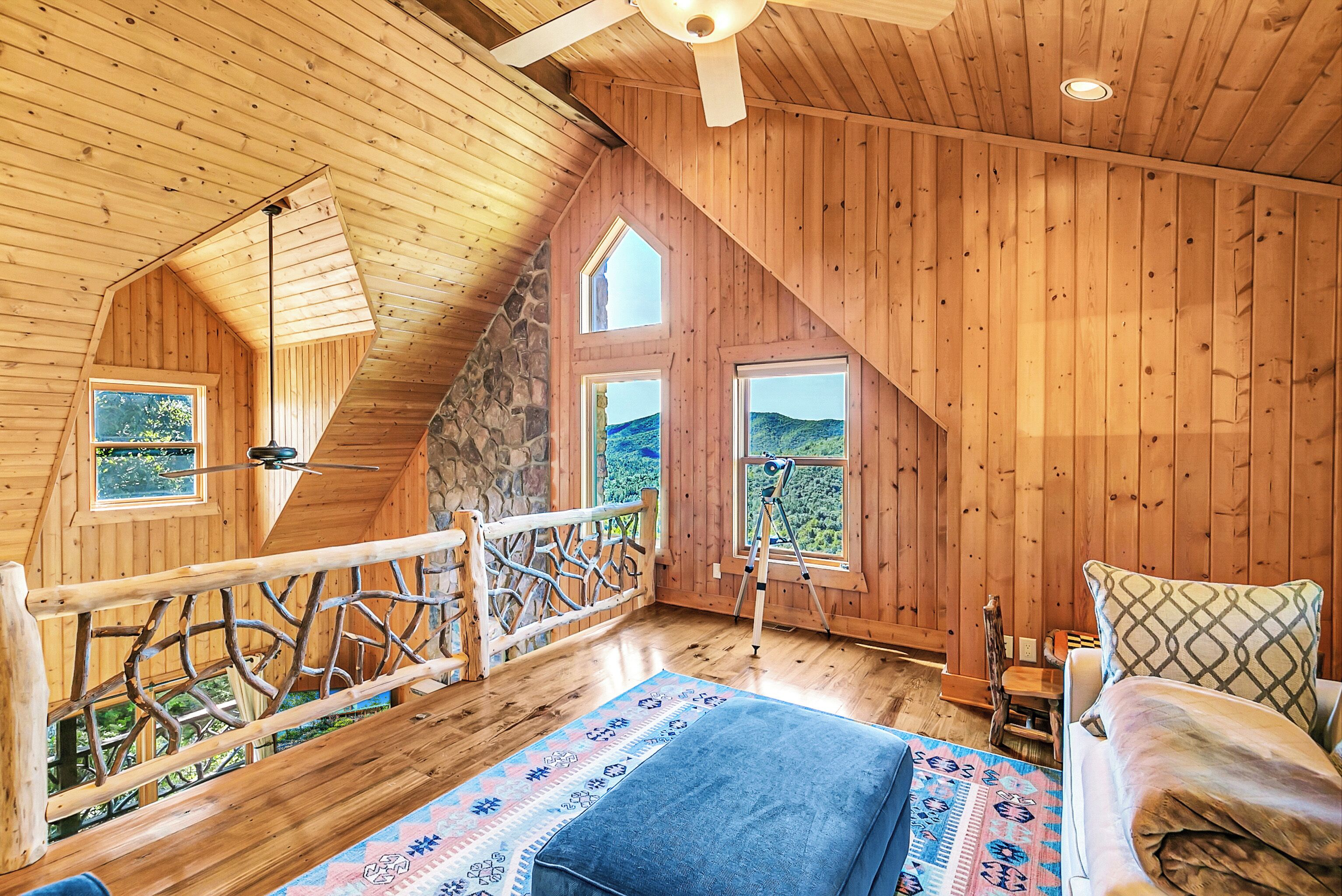 Une chambre confortable située dans les combles, avec des murs en bois, un plafond en pente et de grandes fenêtres offrant une vue panoramique.