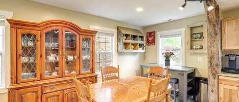 A dining area with a wooden table and chairs, a china cabinet, and a rustic wooden column.