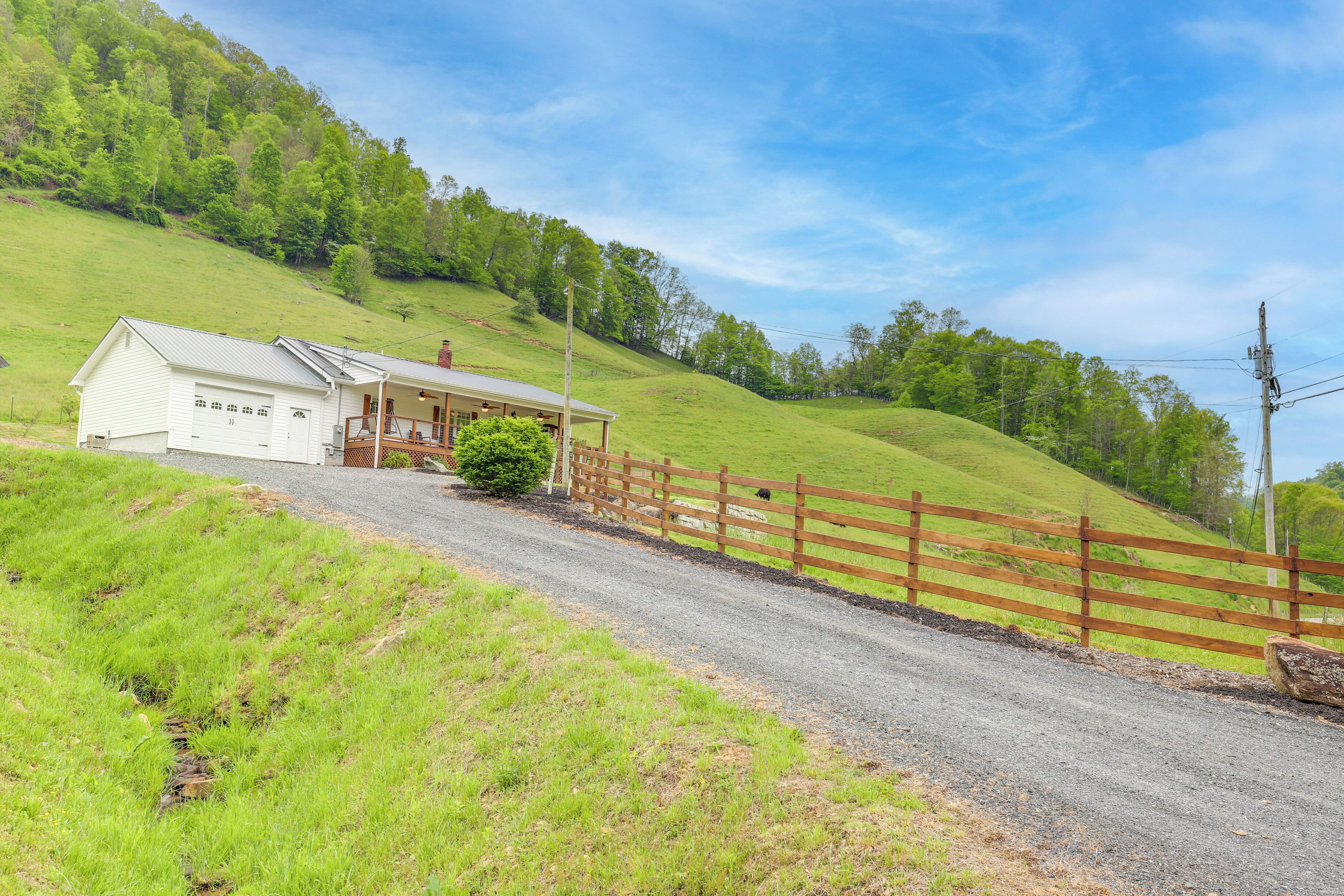 A rural property with a white garage, a wooden fence, and a gravel driveway.