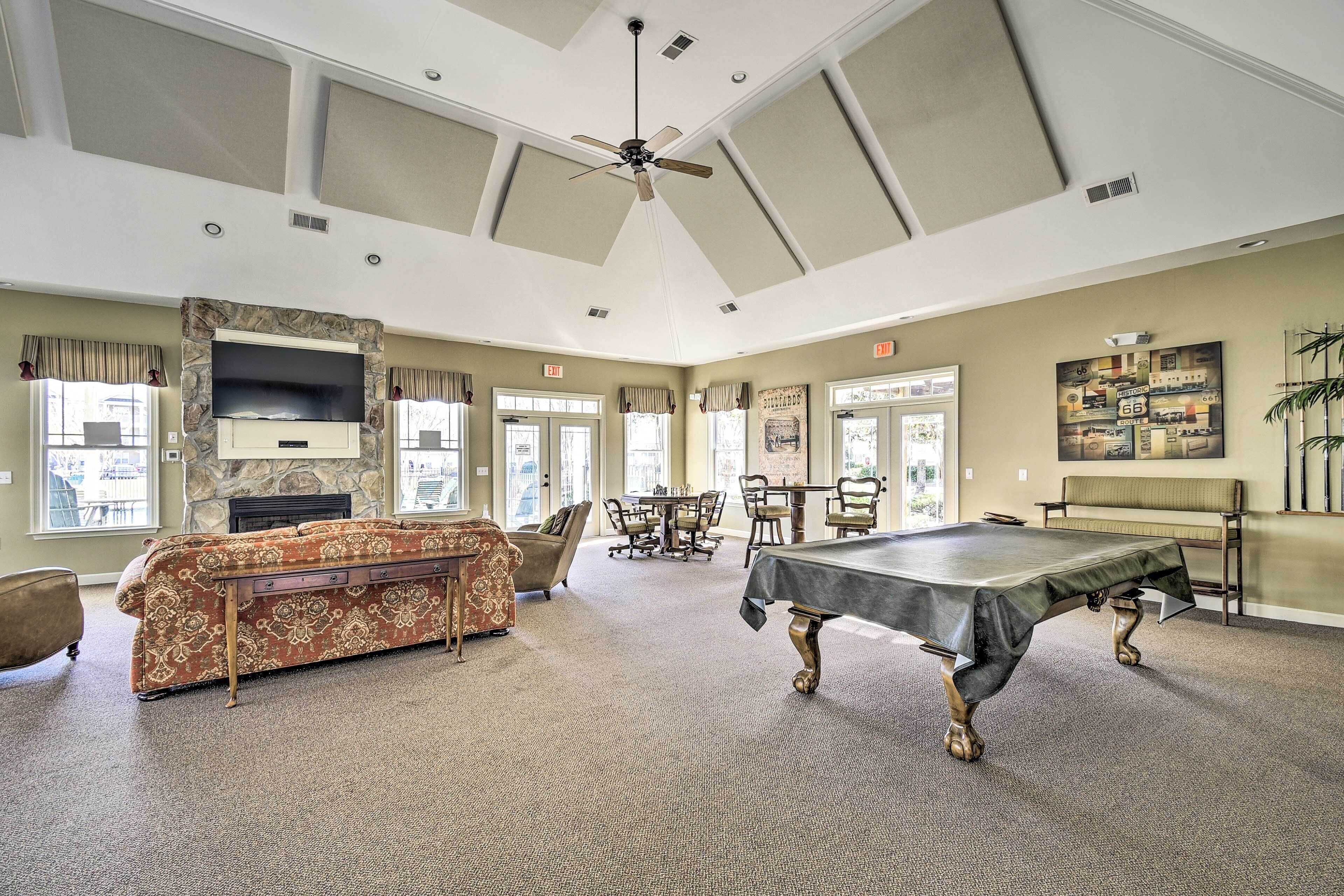 A spacious room with a pool table, a sofa, and a television mounted on a stone wall.