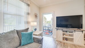 Ein Wohnzimmer mit einer Couch, einem Fernseher und einem kleinen Tisch mit einer Lampe.