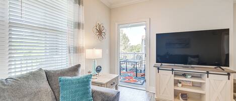 A living room with a sofa, TV, and a small table with a lamp.