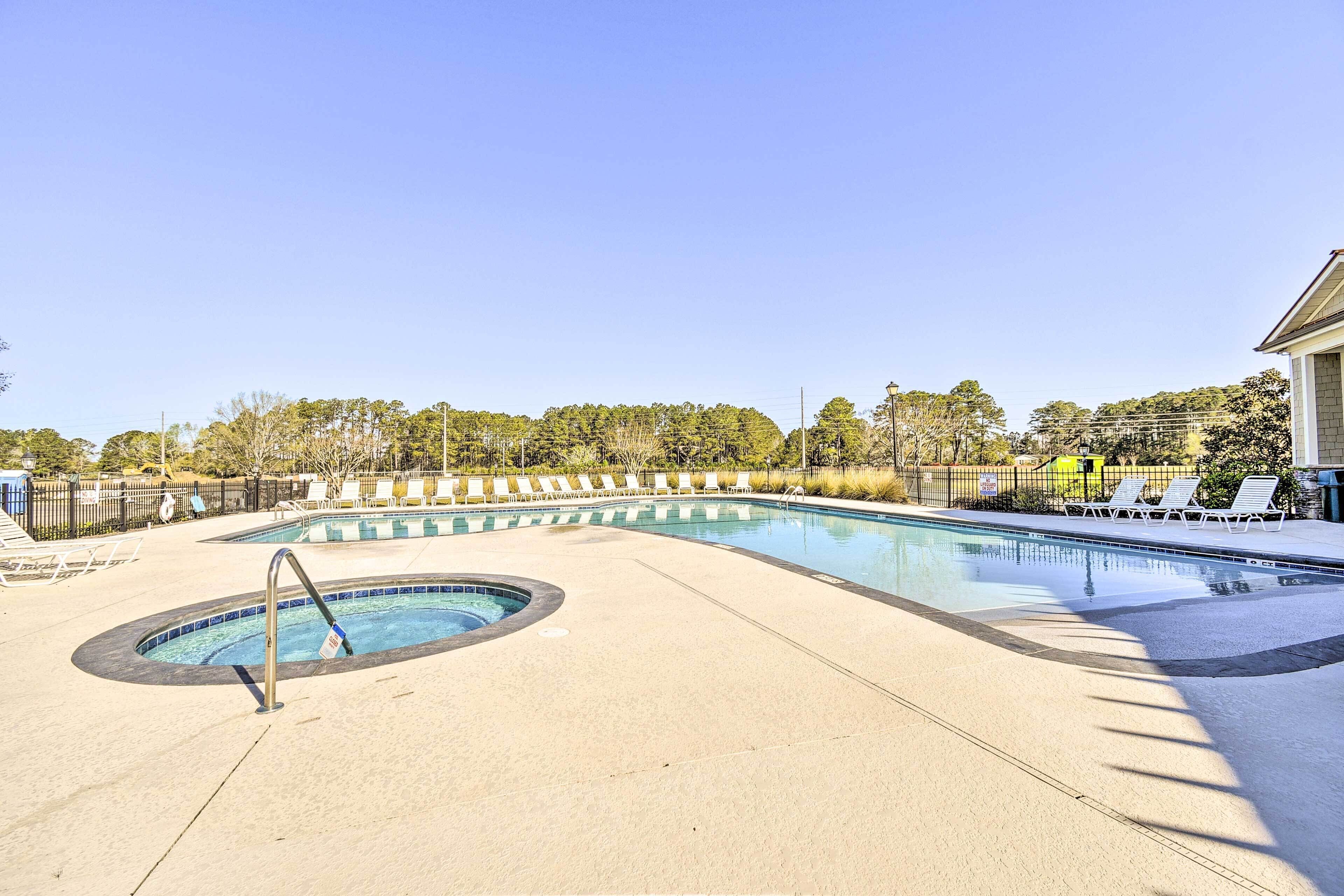 A swimming pool with lounge chairs and a hot tub.