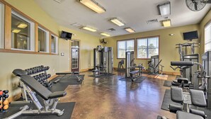 Ein Fitnessstudio mit verschiedenen Trainingsgeräten, darunter Kurzhanteln, Bänke und Kraftgeräte.