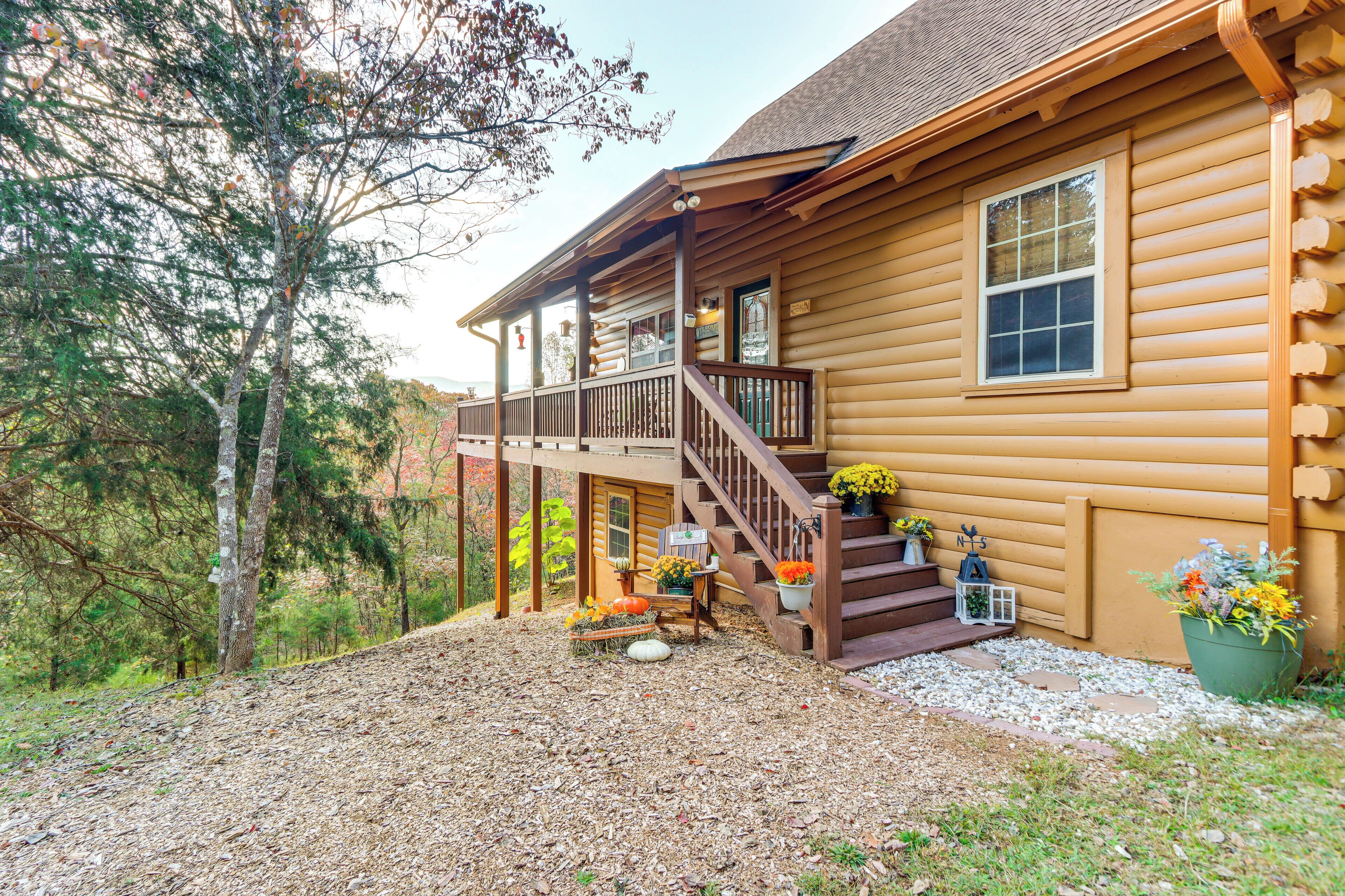 A log cabin with a porch, a staircase, and a small garden area with potted plants.
