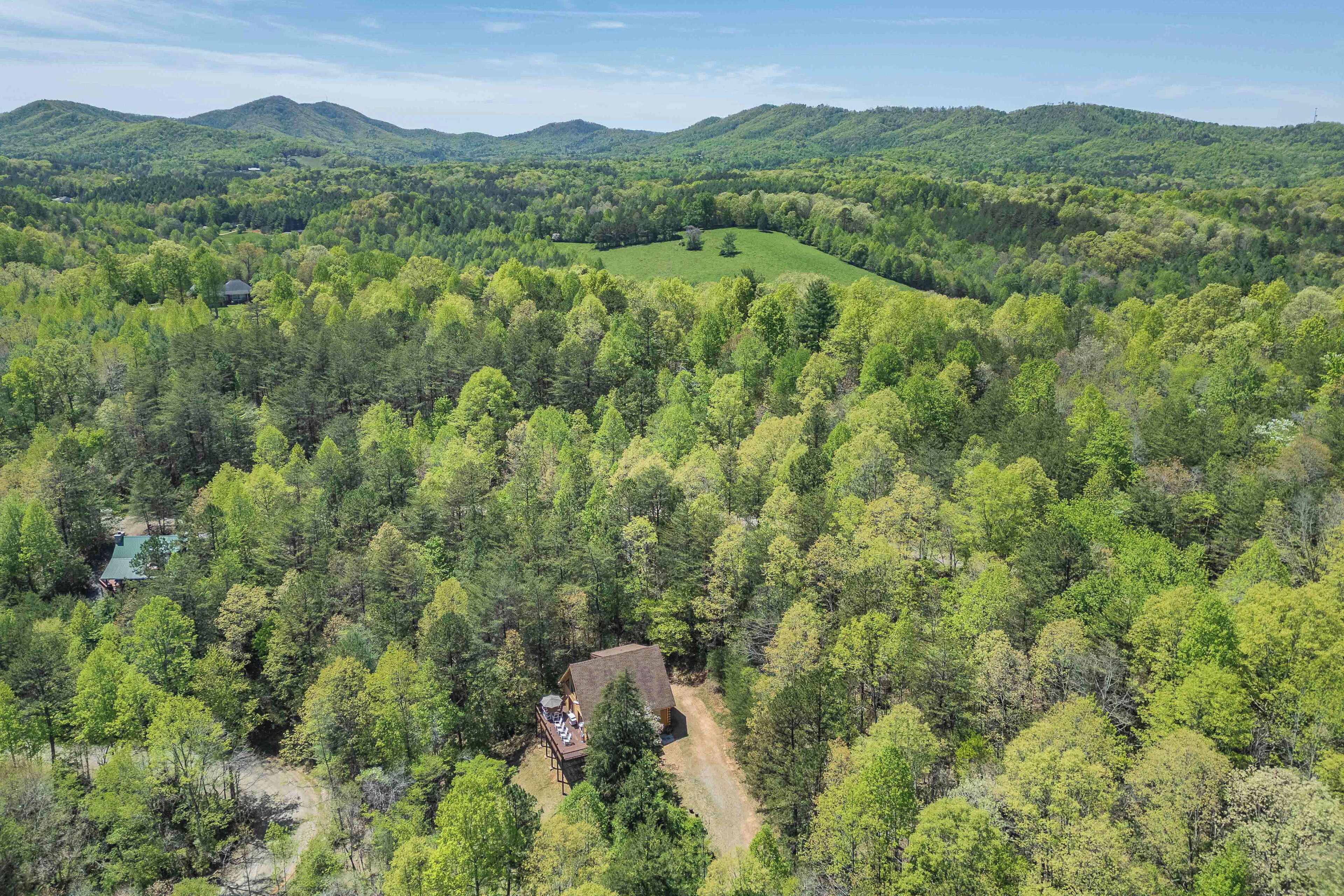 A remote cabin surrounded by dense forest, with a clear view of the surrounding hills.