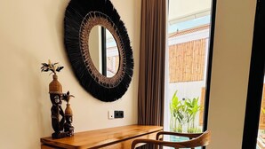 Una habitación moderna con una consola de madera, una silla, una cesta tejida y un espejo grande en la pared.