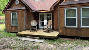 Eine Holzhütte mit Veranda, zwei Schaukelstühlen und einer Tür mit Glasfenster.