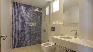 A modern bathroom with a shower, toilet, and sink.