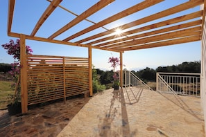 A wooden pergola structure with a stone floor, surrounded by potted plants and a view of the landscape. - Faralya Tuz Hotel (Fethiye)