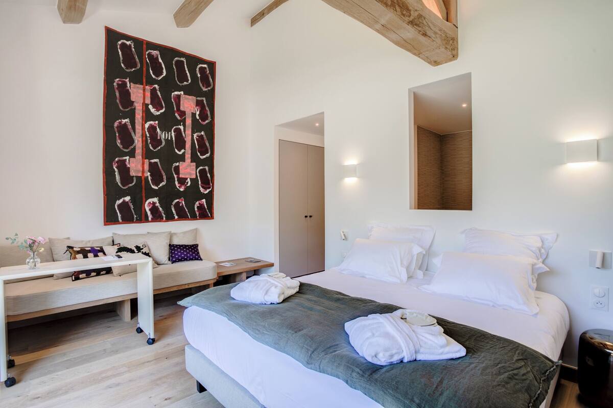 A modern hotel room with a large bed, a desk, and a unique abstract painting.