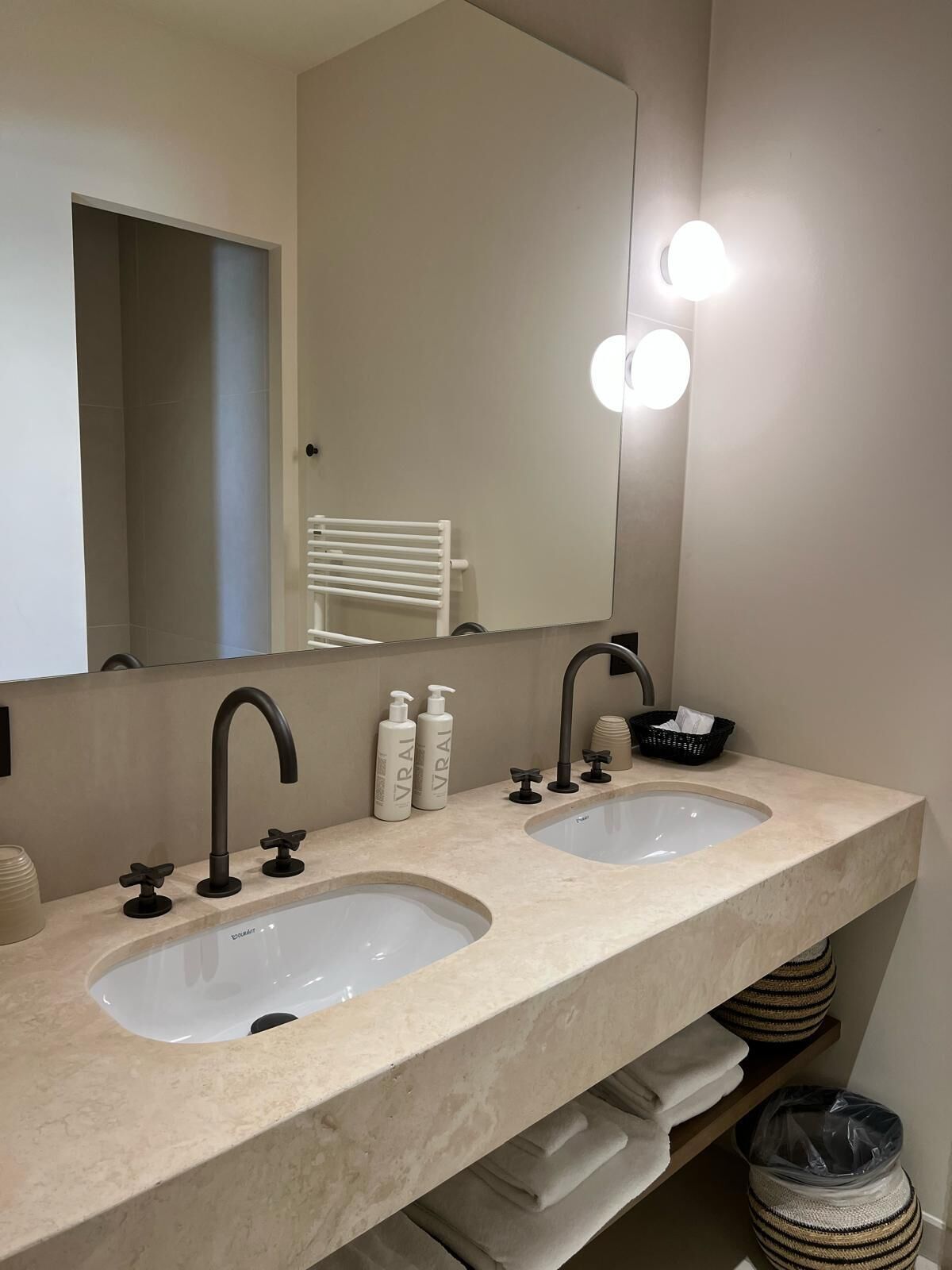 A bathroom with two sinks, a mirror, and a towel rack.