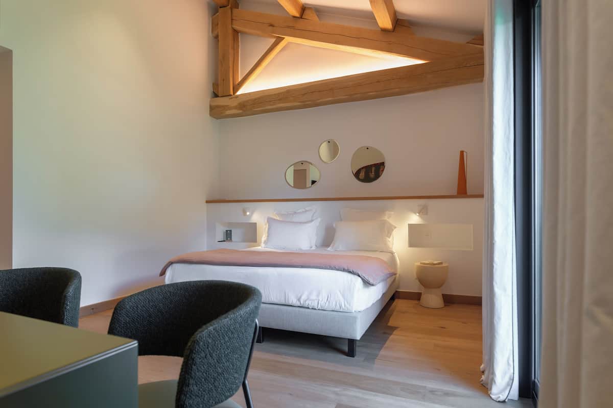 A modern bedroom with a bed, bedside tables, a desk, and chairs.