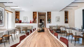 Un comedor amplio con una larga mesa de madera, múltiples sillas y estanterías empotradas con libros y objetos decorativos.