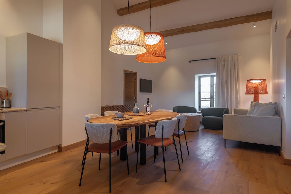A modern dining area with a wooden table, chairs, and pendant lights.