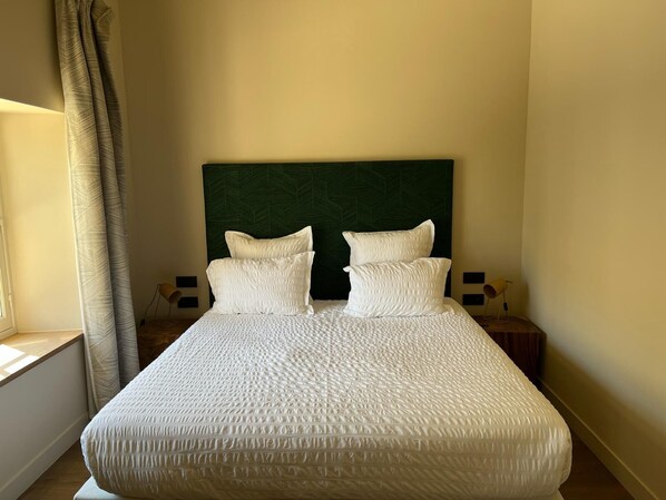 A neatly made bed with white bedding and pillows, a green headboard, and bedside lamps. - Domaine de Panéry (Pouzilhac)