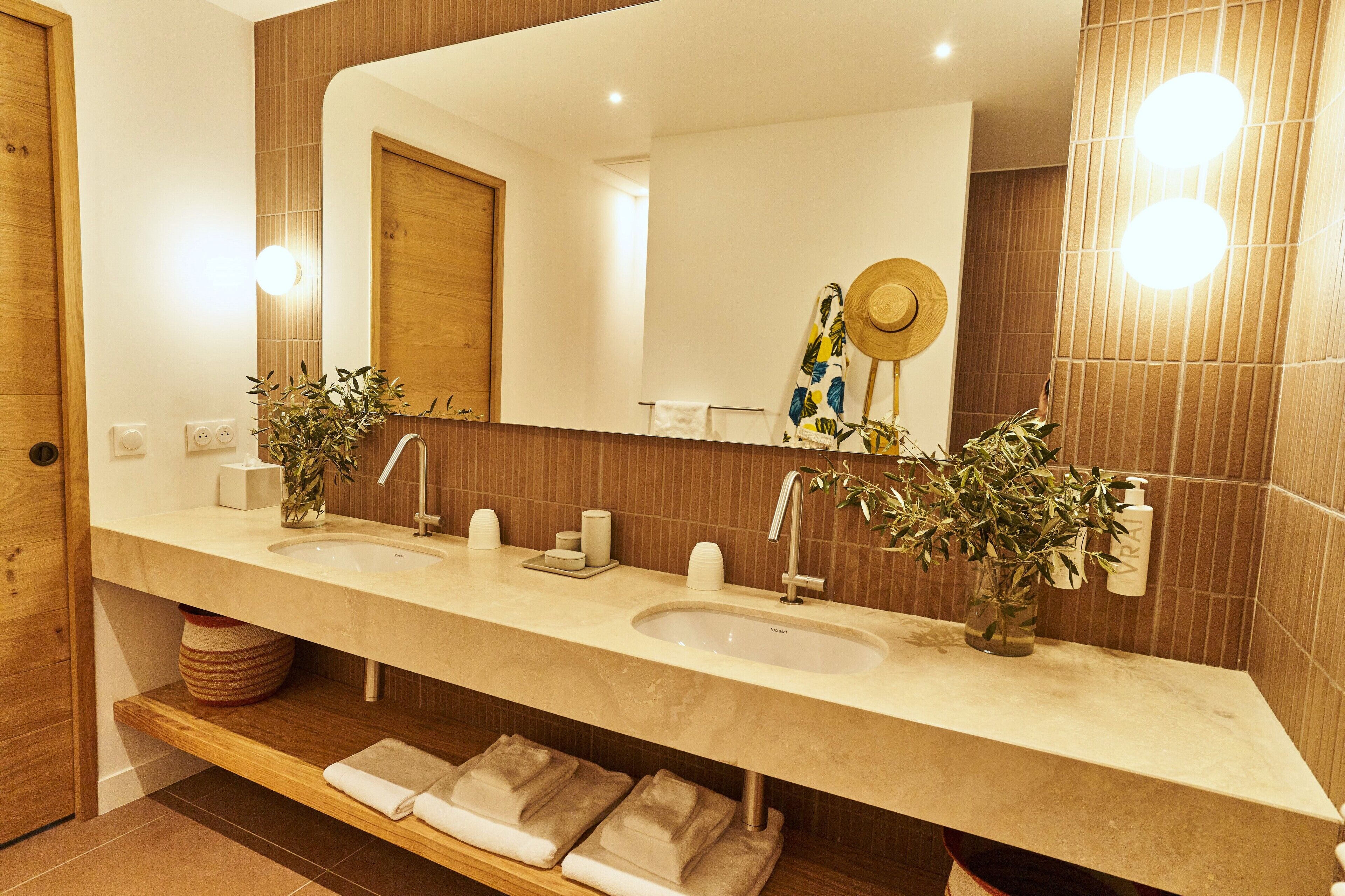 Un bagno moderno con un ampio specchio, due lavabi e dettagli in legno.