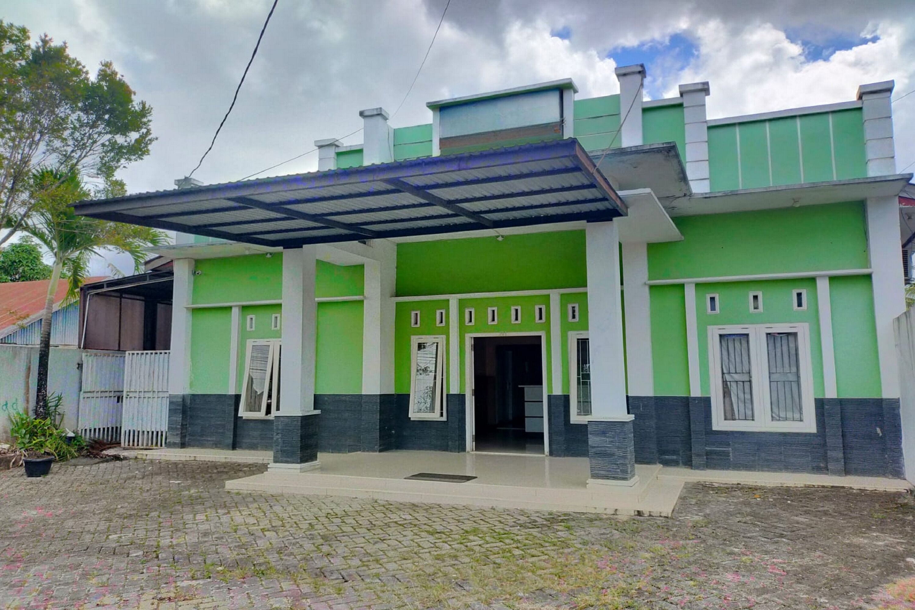 A two-story house with a green and white exterior, a covered entrance, and a paved driveway.