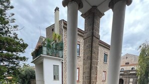 A covered outdoor patio with a table and chairs, stone flooring, and a view of a historic building with columns. - Bed & breakfast in sorrento with pool and spa (Sorrento)
