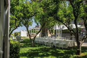 An outdoor seating area with tables and chairs arranged under trees, overlooking a building with a stone facade. - Bed & Breakfast in Sorrento with a Pool and Spa (Sorrento)