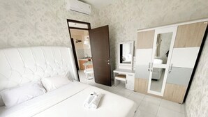 A hotel room with a large bed, a desk, a wardrobe, and a bathroom visible through an open door. - OYO 93940 Apartemen Mekarwangi Square By Lina (Bandung)