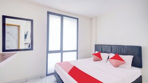 A modern hotel room with a large bed, a desk, and a large window. - Hotel O J&B Smart Jatinegara (Jakarta)