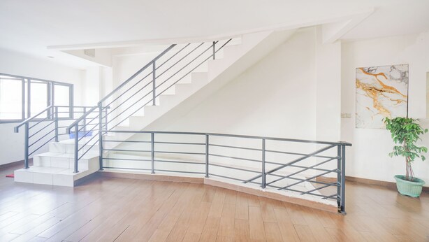 A modern interior with a staircase, wooden flooring, and a potted plant. - Hotel O J&B Smart Jatinegara (Jakarta)