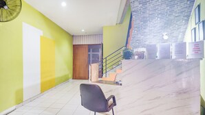 A room with a tiled floor, a chair, a fan, a wooden door, and a staircase with a brick wall. - Hotel O J&B Smart Jatinegara (Jakarta)