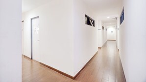 A long, narrow hallway with white walls and wooden flooring. - Hotel O J&B Smart Jatinegara (Jakarta)
