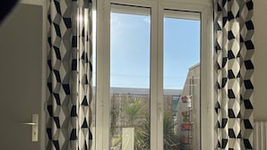 Une chambre à coucher avec un lit, des rideaux et une vue à travers une porte vitrée.