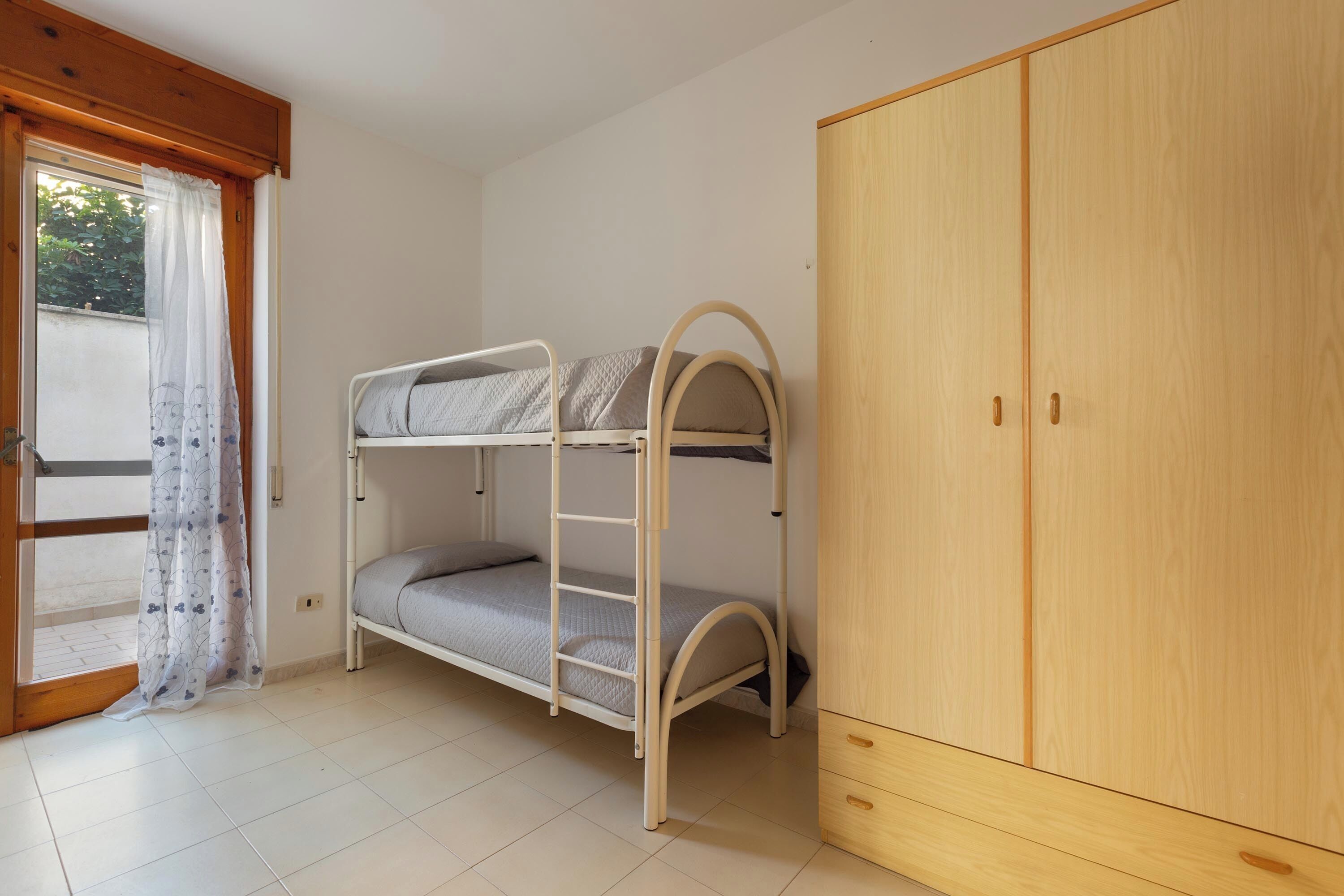 A bunk bed with a wooden wardrobe beside it.
