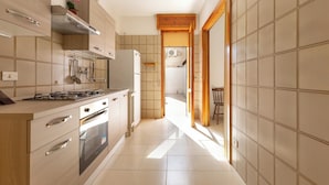 A modern kitchen with a gas stove, oven, and a wooden cabinet. - 3886 Villino Paradiso by Babarhouse (Porto Cesareo)
