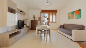 A modern living room with a TV, dining table, and sofa. - 3886 Villino Paradiso by Babarhouse (Porto Cesareo)