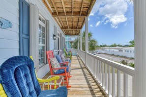 A covered porch with colorful chairs and a view of a residential area. - Spacious 5 bedroom, 4.5 bathrooms w/pool, plus $100 golf cart reimbursement (Garden City Beach)