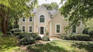 A two-story house with a symmetrical facade, a central entrance with a door, and a small porch. - NEW Southern Charm ATL 4 Bdr/3 Bath Executive Home (Norcross)