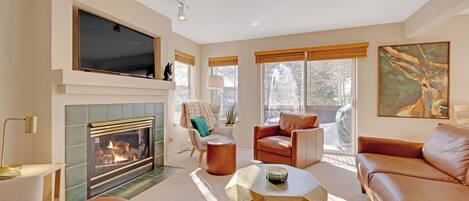 A modern living room with a fireplace, leather sofas, a coffee table, and a large flat-screen TV.