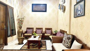 A traditional living room with a sofa, chairs, a coffee table, and a decorative vase. - Collection O 93942 Griya Singgah Berkah Syariah (Kutoarjo)