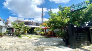 A courtyard with a paved area, a covered seating area, and a sign indicating a nearby establishment. - Collection O 93942 Griya Singgah Berkah Syariah (Kutoarjo)