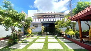 A hotel entrance with a checkered pathway leading to the door, surrounded by potted plants and a pergola. - Collection O 93942 Griya Singgah Berkah Syariah (Kutoarjo)