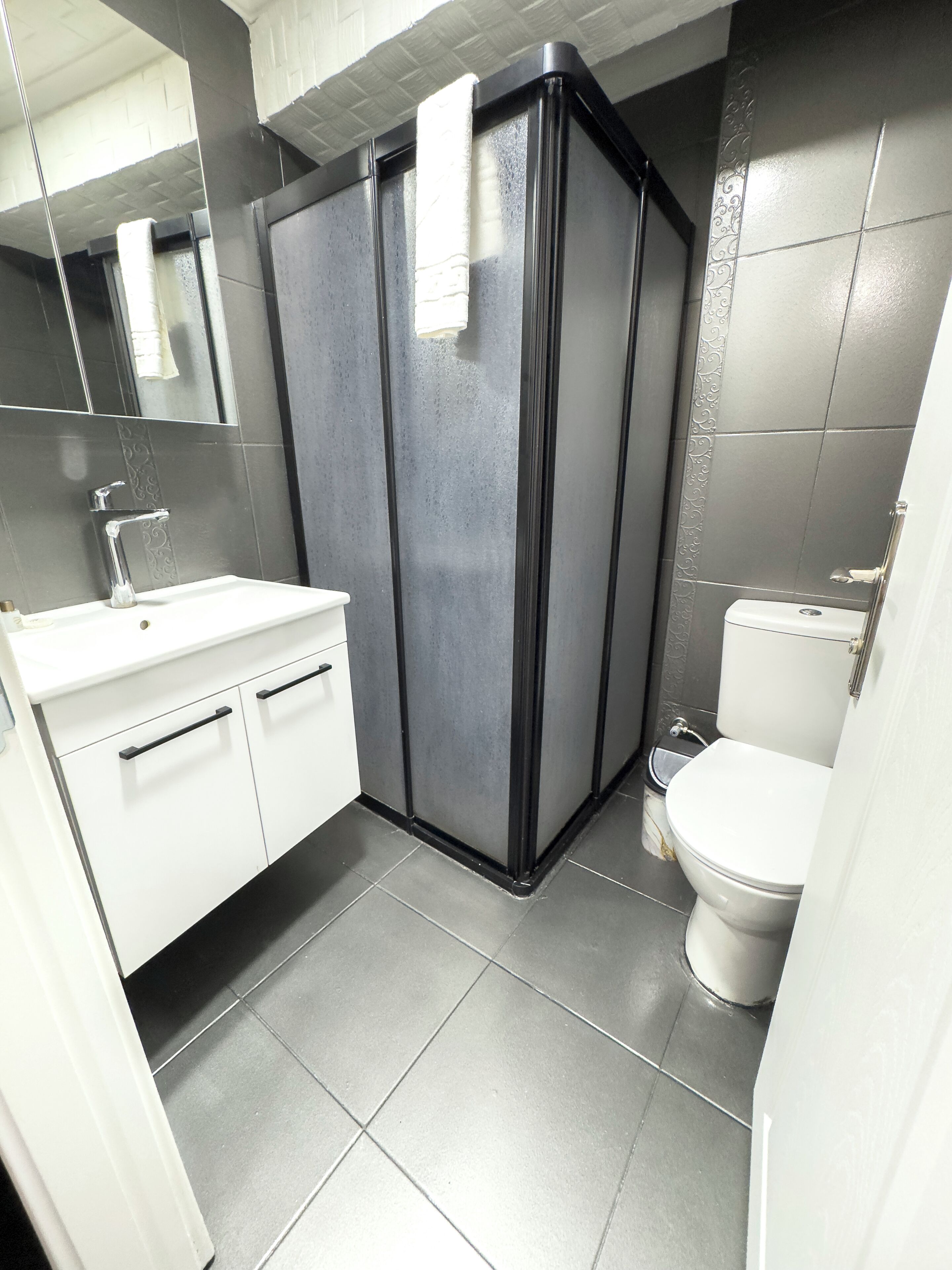 Un baño moderno con lavamanos blanco, inodoro y cabina de ducha.