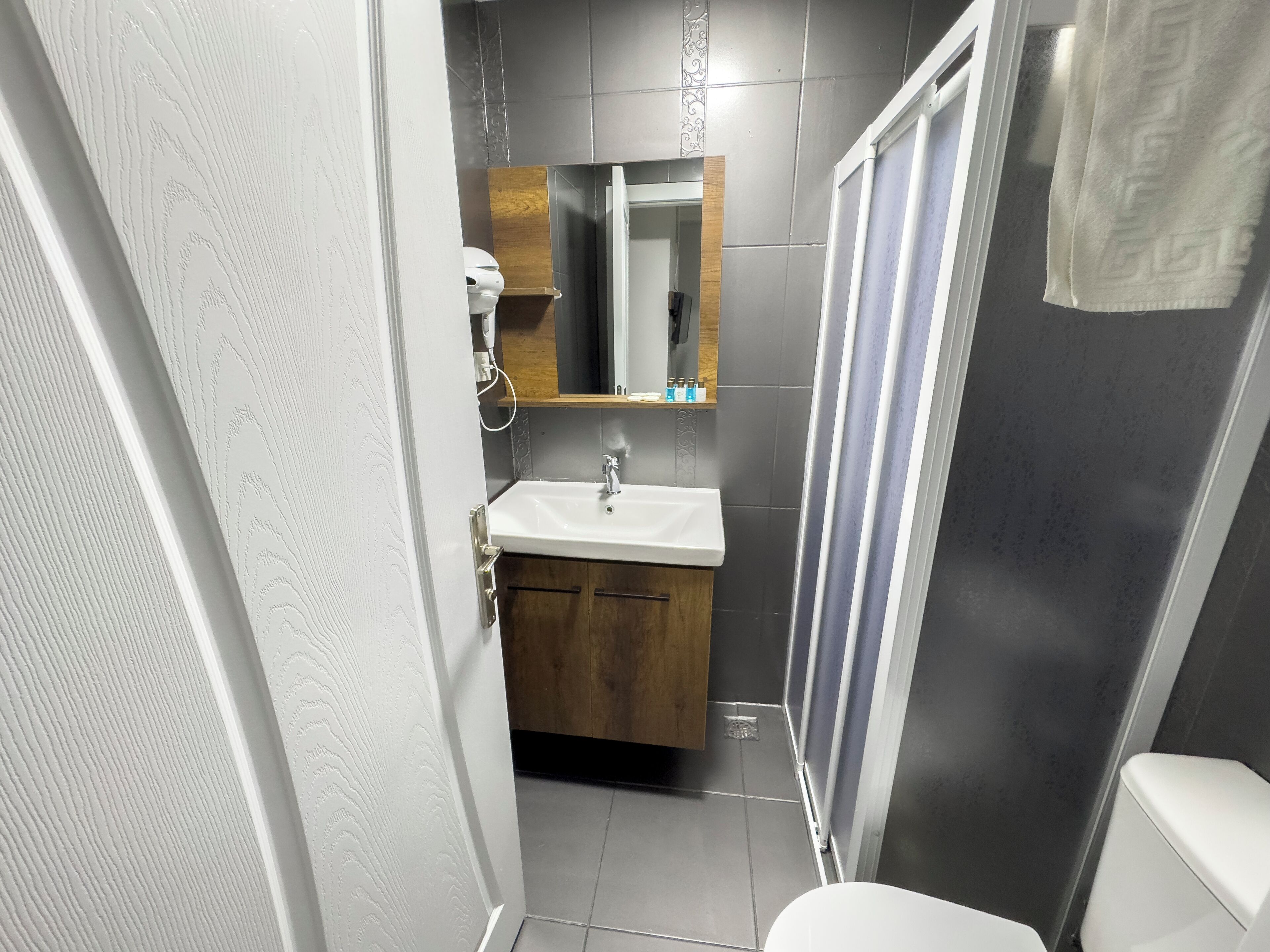 Un baño con un lavamanos blanco, armarios de madera, un espejo y una cortina de ducha.