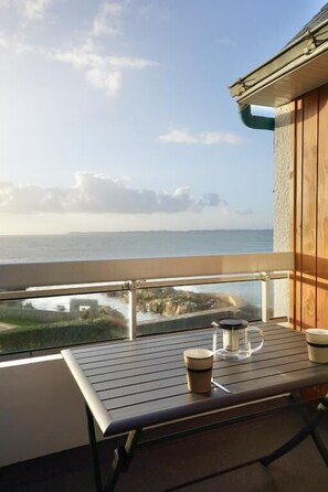 A balcony with a table, a glass container, and a cup.