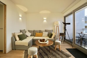 A modern living room with a sectional sofa, a round coffee table, a floor lamp, and a tripod.