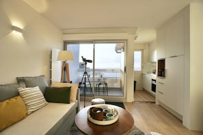A modern living room with a sofa, a coffee table, and a balcony with a view.