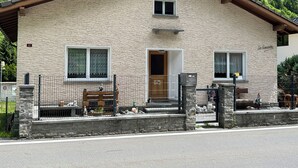 A stone building with a wooden door and windows, a bench outside, and a stone wall in front. - Urlaub im Schönen Calancatal (Augio)