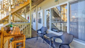 Un espace extérieur abrité, aménagé avec du mobilier en bois et doté d’un escalier menant à un niveau supérieur.