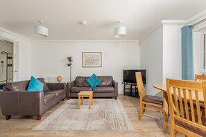 A modern living room with a sofa, two chairs, a coffee table, and a TV. - Kingsbarns House (No 1) (St Andrews)